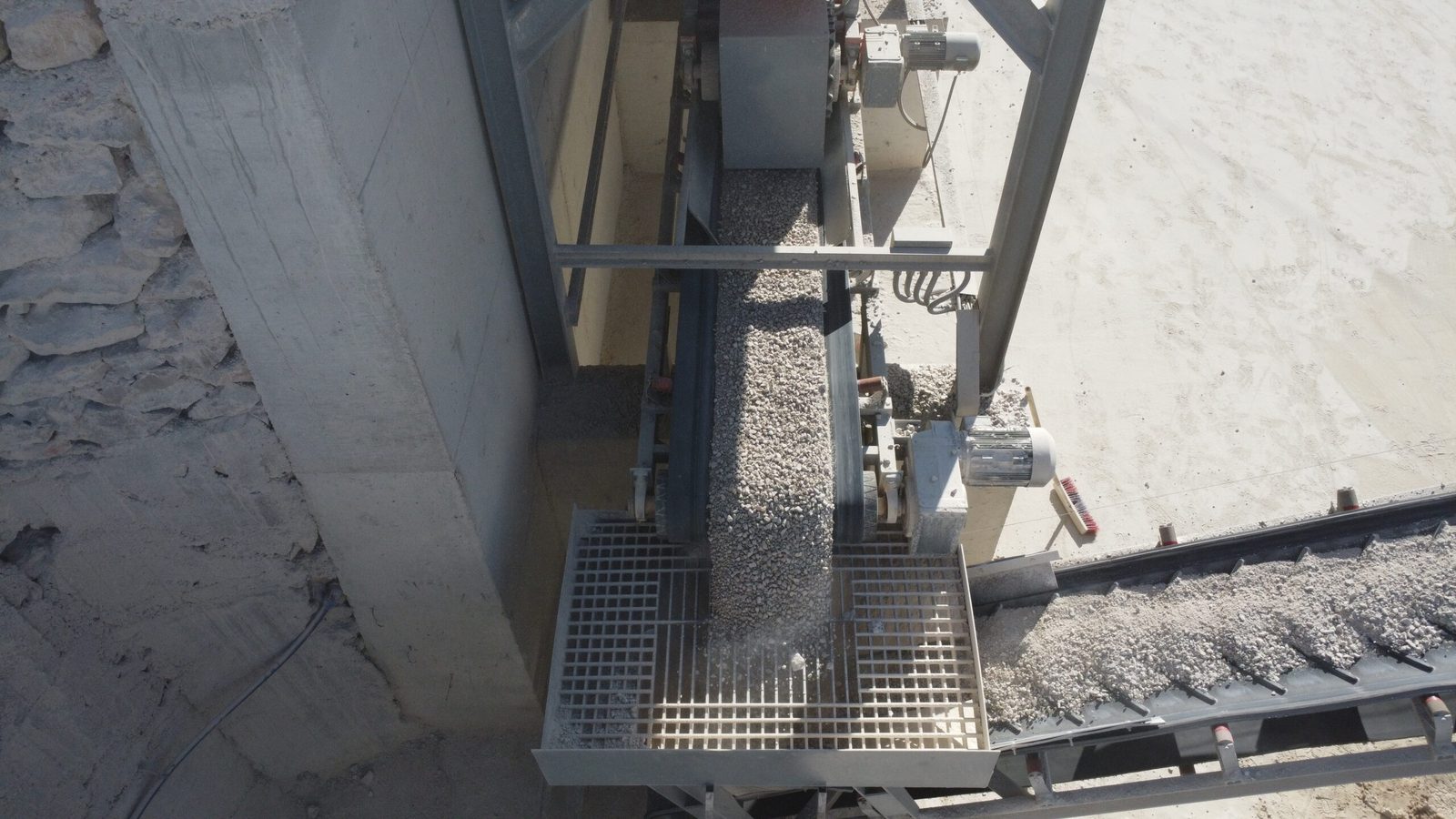 Transfer point where aggregate drops onto the collecting conveyor in a wet mix macadam plant
